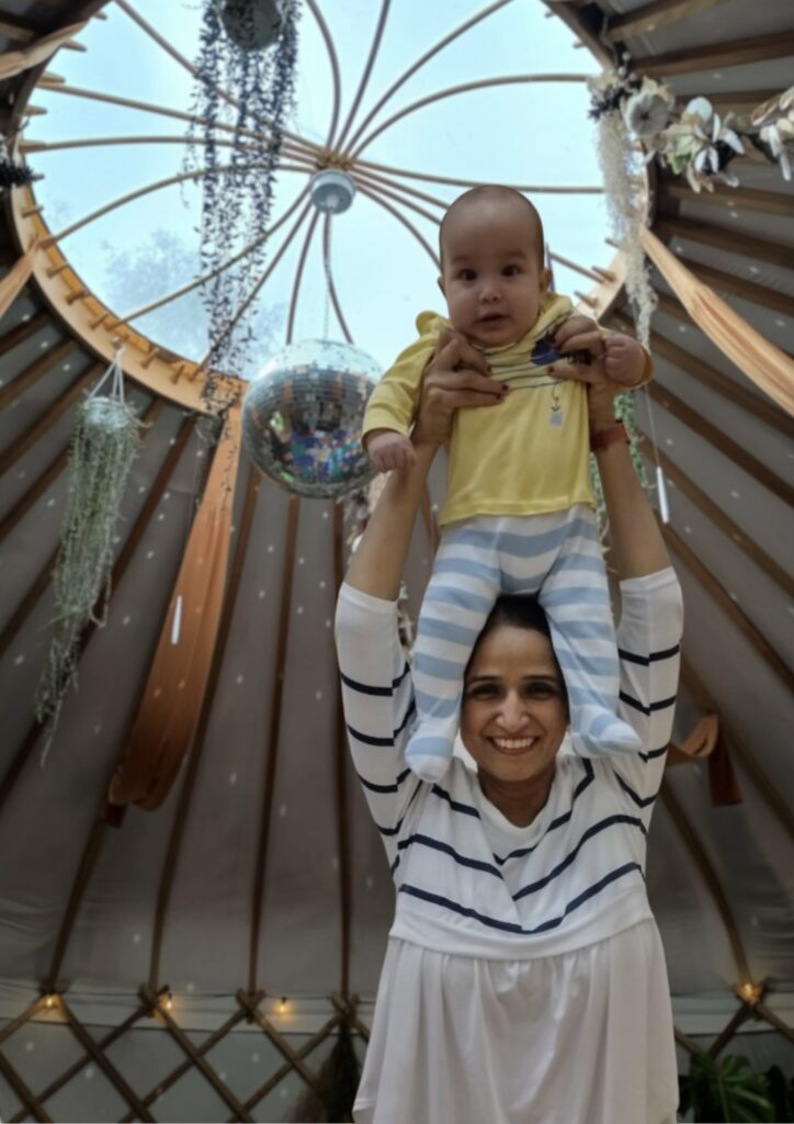 Happy mum at baby yoga class holding her baby high